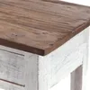 A close-up view of the corner of a wooden table with a distressed white base and a natural wood top. Náhled obrázku produktu