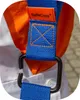 A close-up view of a blue and orange strap with a metal hook, attached to a white garment. Produktbild-Vorschau