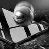 A reflective sphere is shown on a surface with a carbon fiber pattern, possibly demonstrating impact resistance. Produktbild-Vorschau