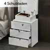 A white nightstand with multiple drawers and an open top compartment, placed next to a bed. Produktbild-Vorschau
