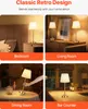 A collage of four images showing a gold table lamp in different home settings: bedroom, living room, dining room, and bar counter. Produktbild-Vorschau