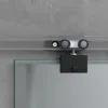 A close-up view of a sliding door mechanism attached to a glass door, set against a concrete wall. Produktbild-Vorschau