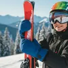 A young person in ski gear holding skis on a snowy mountain. Produktbild-Vorschau