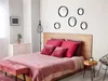 A bedroom scene with a bed, dresser, and decorative mirrors on the wall. Produktbild-Vorschau