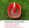 A red hand spreader filled with granular material, placed on a green lawn. Produktbild-Vorschau