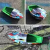 A small toy boat made from recycled materials, placed on a concrete surface with graffiti. Produktbild-Vorschau
