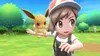 A young girl with a hat and backpack is holding a small, furry creature in her outstretched arm in a grassy, outdoor environment. Produktbild-Vorschau