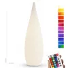 A tall, white, tear-drop shaped LED lamp is shown standing upright on a white background. A remote control is held in a hand in the bottom right corner, and a color swatch chart is displayed to the right of the lamp. Produktbild-Vorschau