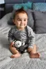 A baby sitting on a bed holding a stuffed toy. Náhľad obrázku produktu