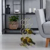 A modern living room setting with a gold wine rack holding bottles, a woven basket with a plant, and a gray armchair. Produktbild-Vorschau