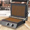 A close-up shot of an open electric grill on a wooden surface, with a kitchen background. Voir les images du produit