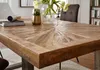 A close-up view of a wooden dining table with a sunburst pattern, set in a dining room with a chair and bookshelf in the background. Anteprima dell’immagine prodotto