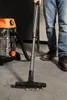 A person is vacuuming debris from a concrete floor with a wet/dry vacuum cleaner. Náhled obrázku produktu