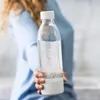 A person is holding a clear water bottle with a white cap and base. Produktbild-Vorschau