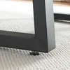 Close-up of the black metal leg of a table with an adjustable foot on a textured rug. Anteprima dell’immagine prodotto