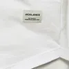 A close-up view of a white t-shirt with a brand label. Produktbild-Vorschau