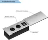 A close-up, angled view of a silver and black power strip with two electrical outlets and two USB ports, with its aluminum sliding cover partially open. Produktbild-Vorschau