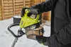 A person is holding a battery-powered snow blower in a snowy outdoor setting. Produktbild-Vorschau