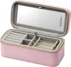 An open pink jewelry box with compartments and a mirror inside. Voir les images du produit