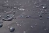 Close-up of water droplets on a dark gray textured surface. Produktbild-Vorschau