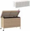 A beige poly rattan garden storage box with its lid open, shown with a stack of white cushions above it. The box has wheels. Podgląd zdjęcia produktu