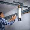 A man is working on a garage ceiling with a work light hanging above him. Produktbild-Vorschau