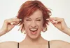 A woman is holding earplugs to her ears. Produktbild-Vorschau