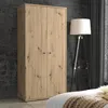 A wooden wardrobe is shown in a room with a floor lamp. Voir les images du produit