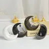 Four decorative moon-shaped night lights with stars are displayed on a surface in front of a white curtain with fairy lights. Produktbild-Vorschau