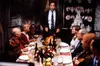 A family gathered around a dining table for a holiday meal, with a man standing and addressing them. Podgląd zdjęcia produktu