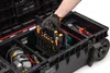 A person's hand wearing a glove is reaching into a large black tool box, organizing screwdrivers. Náhled obrázku produktu