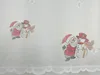 A close-up of a white lace curtain with printed Christmas-themed images of Santa Claus and a snowman. Produktbild-Vorschau