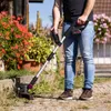 A person is using a cordless trimmer in a garden setting. Produktbild-Vorschau