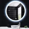 A round LED mirror above a sink in a bathroom. Voir les images du produit