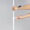 Two hands adjusting a white pole with a locking mechanism. Produktbild-Vorschau