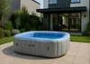 An inflatable hot tub is set up on a patio in a modern backyard, with a house and landscaping in the background. Podgląd zdjęcia produktu