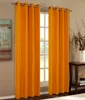 Two orange curtains hang on a window rod, framing a window with white mullions. A painting hangs on the wall to the left, and a wooden table with decorative items is on the right. Produktbild-Vorschau