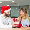 A man in a Santa hat gives a gift to a woman wearing tinsel. Anteprima dell’immagine prodotto