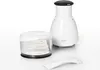A white manual food chopper and a clear measuring cup with red markings are displayed on a white background. Produktbild-Vorschau