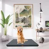 A golden retriever dog sits on an anthracite orthopedic dog bed in a room with a large painting on the wall and a desk with a computer. Produktbild-Vorschau