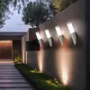 Modern outdoor walkway with wall-mounted lights illuminating the path and surrounding greenery. Produktbild-Vorschau
