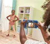 A child is taking a picture of another child with a toy camera in a room. Produktbild-Vorschau