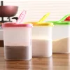 Three spice shakers with colorful lids are lined up on a wooden surface in a kitchen setting. Produktbild-Vorschau