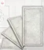 Several decorative wall panels are arranged in a fanned-out display against a white, vertically paneled wall. A framed piece of art with a line drawing is visible on the left. Produktbild-Vorschau