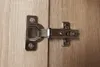 A close-up view of a cabinet hinge attached to two wooden surfaces. Náhľad obrázku produktu
