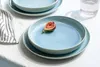 A light blue plate with a fig on it, set on a white tablecloth. Produktbild-Vorschau