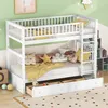 A white wooden bunk bed with drawers underneath, decorated with colorful pillows and blankets, in a child's room.