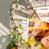 A close-up view of a miniature dollhouse attic with a spiral staircase adorned with artificial roses and vines. Anteprima dell’immagine prodotto