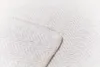 A close-up view of a white blanket with a herringbone pattern and a stitched edge. Produktbild-Vorschau