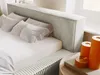 A close-up view of a bed with pillows and decorative candles on a side table. Produktbild-Vorschau